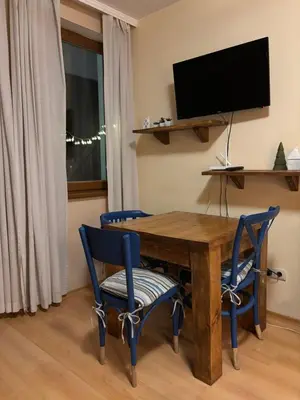 a dining room table with two blue chairs and a television at Studio Kris Villa Park in Borovets
