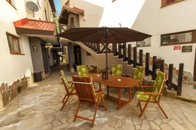 a wooden table and chairs with an umbrella on a patio at Monastery 2 Aparthotel in Pamporovo