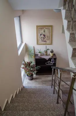 a room with a staircase with a table and potted plants at Guest House Dinevi in Sapareva Banya