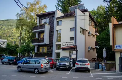 a parking lot with cars parked in front of a building at Guest House Dinevi in Sapareva Banya