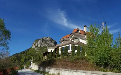 a house on a hill with a mountain in the background at Семеен хотел Кристал in Smolyan