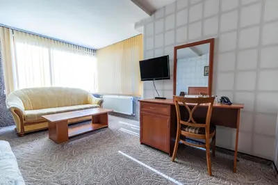 a living room with a couch and a desk with a mirror at Семеен хотел Кристал in Smolyan