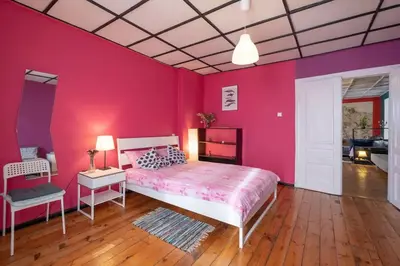 a bedroom with pink walls and a bed and a table at Cool Central Apartment in Sofia