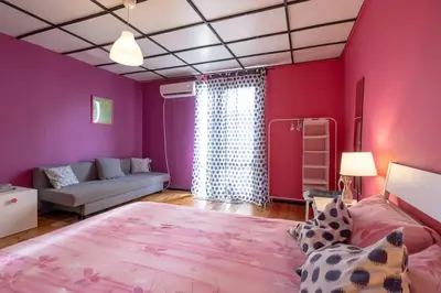 a bedroom with pink walls and a bed and a couch at Cool Central Apartment in Sofia