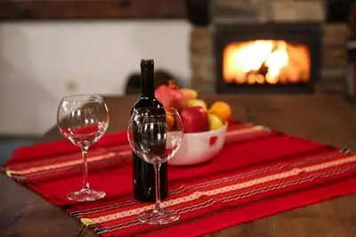 a bottle of wine and two wine glasses on a table at Yancheva Guest House in Delchevo