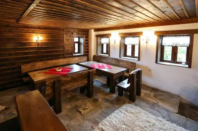 a room with a table and benches in a cabin at Yancheva Guest House in Delchevo