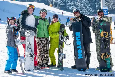 a group of people standing in the snow holding snowboards at Borovets Gardens Apartments in Borovets