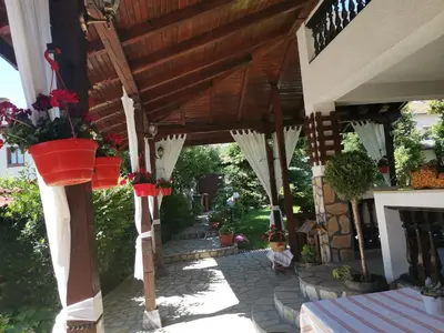 a patio with white umbrellas on a house at Boutique Guest House IKONOMOV in Bansko