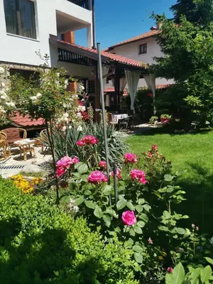a garden in front of a house with pink flowers at Boutique Guest House IKONOMOV in Bansko
