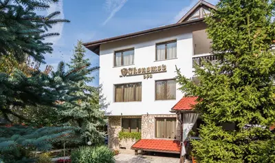 a large white building with a sign on it at Boutique Guest House IKONOMOV in Bansko