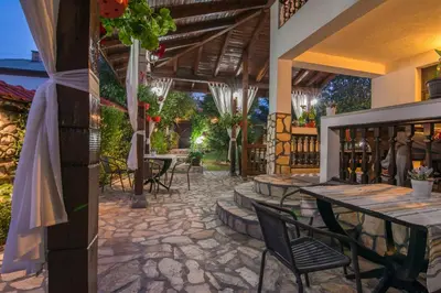 an outdoor patio with tables and chairs and a bar at Boutique Guest House IKONOMOV in Bansko