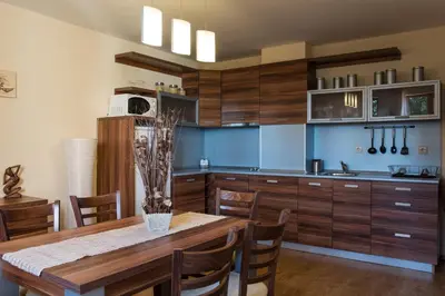 a kitchen with wooden cabinets and a wooden table with chairs at Mountain Lake Hotel in Smolyan