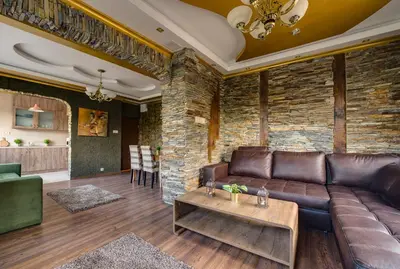a living room with a leather couch and a stone wall at Unique atmosphere with golden standard design in Sofia