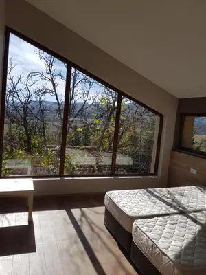 a bedroom with a bed and a large window at Mihaylova kushta in Lyubosh