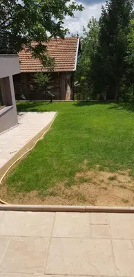 a grassy yard with a building and a house at Mihaylova kushta in Lyubosh