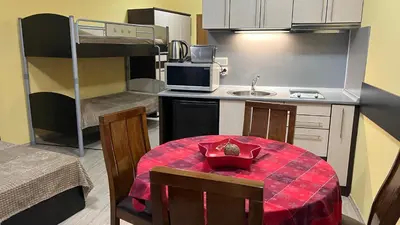 a small kitchen with a table and a room with a bunk bed at Apartments & Rooms Royal Plaza in Borovets