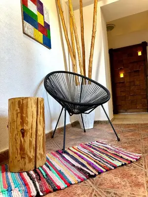 a black chair sitting on a rug next to a wooden stump at Red House Family house in Bansko