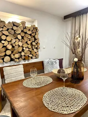 a wooden table with two wine glasses and a pile of logs at Red House Family house in Bansko