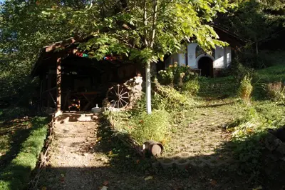 a barn with a wheel in front of a tree at Balkanski chanove in Botevgrad