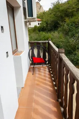 a bench on a balcony with a red pillow at Apartment R. Dermendzhiev in Melnik
