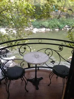 a table and chairs on a porch with a view of a river at Hotel- Restaurant Struma in Stara Kresna