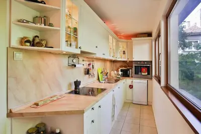 a kitchen with white cabinets and a sink and a window at Portofino Apartment in Sofia