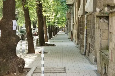 a sidewalk with trees on the side of a building at Portofino Apartment in Sofia