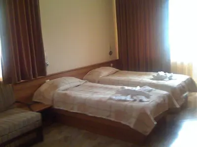 a hotel room with two beds and a couch at Family Hotel Yola in Chepelare