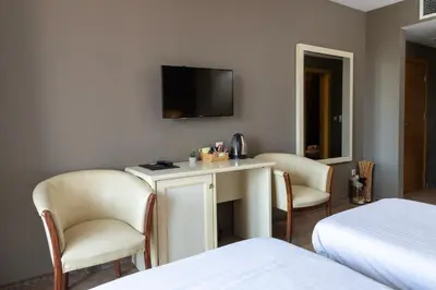 a hotel room with a table and chairs and a tv at St. George Hotel in Sofia