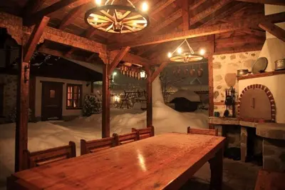 a dining room with a wooden table and a room with snow at Chalet White Fang in Bansko