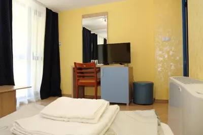 a living room with a tv and a chair at Fenix Family Hotel in Blagoevgrad