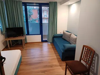 a living room with a blue couch and a tv at Fenix Family Hotel in Blagoevgrad