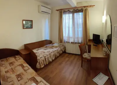 a small room with a bed and a desk and a window at Medic Hotel in Sofia