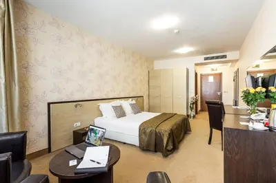 a hotel room with a bed and a desk with a laptop at City Avenue Hotel in Sofia