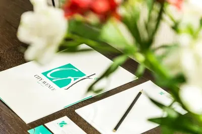 a card with a logo on a table with flowers at City Avenue Hotel in Sofia