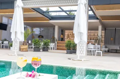 a pool with two glasses of wine and umbrellas at Tsarsko Selo Spa Hotel in Sofia