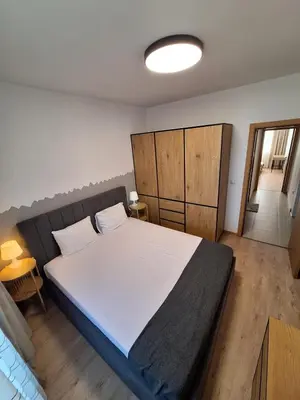 a bedroom with a large white bed with wooden cabinets at Apartments Mladost 1A in Sofia