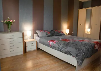 a bedroom with a bed and two dressers and two lamps at Sofia Central Hotel Apartments in Sofia