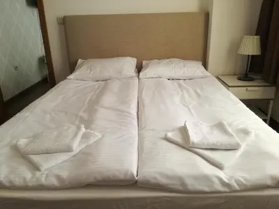 a bed with white sheets and two towels on it at Apartments in Complex Grand Manastira in Pamporovo