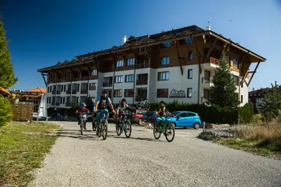 a group of people riding bikes down a road in front of a building at White Lavina - Ski, Bike, Hike in Bansko