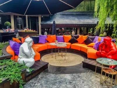 an orange couch with colorful pillows on a patio at Hotel Marinela Sofia in Sofia