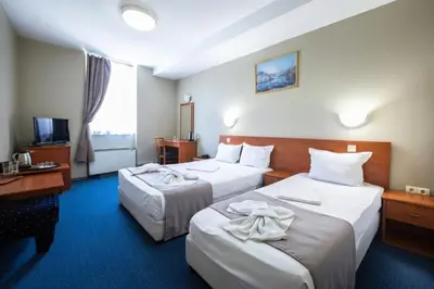 a hotel room with two beds and a desk at Sveta Sofia Hotel in Sofia