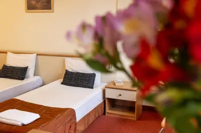 a room with two beds and a vase of flowers at Hotel Brod - Free Parking in Sofia