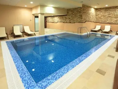 a large swimming pool in a hotel with chairs around it at Royal Park Spa Bansko, private apartments within the complex in Bansko