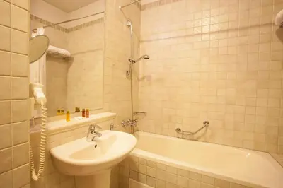 a bathroom with a sink and a tub and a toilet at Hotel Tanne in Bansko