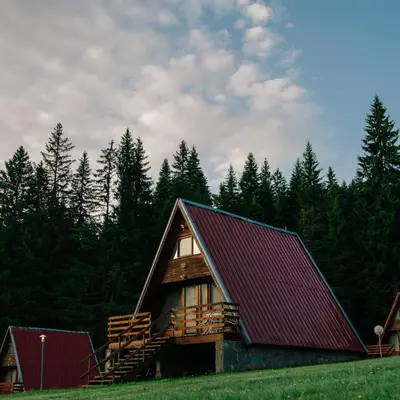 a log cabin with a red roof in a field at Complex Malina Pamporovo in Pamporovo