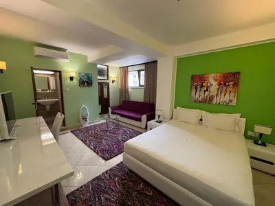 a bedroom with a white bed and a green wall at Hotel Dafi in Plovdiv