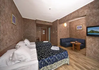 a hotel room with two beds and a couch at Hotel Akord - Free Parking & Metro Access in Sofia