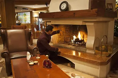 a man sitting in front of a fireplace at Kempinski Hotel Grand Arena Bansko in Bansko