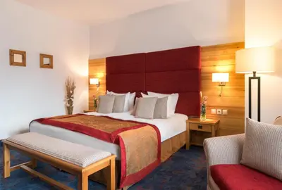a hotel room with a large bed and a chair at Kempinski Hotel Grand Arena Bansko in Bansko